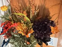 Mixed faux floral stems hanging, showing variety of blooms and foliage