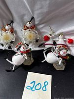 Group view of five ornaments: two top-hat snowmen, two earmuff snowmen, one snowflake