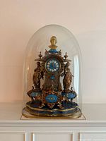 Full view of ormolu and porcelain mantel clock under glass dome