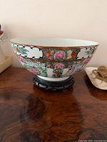 Side view of porcelain bowl on wood stand showing decoration