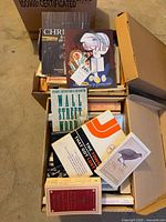 Two boxes filled with assorted books, visible titles include Wall Street Words and The Town That Got Lost