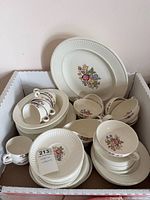 Box containing stacked plates, bowls, cups, saucers and serving platter in Wedgwood Cavalier Edme pattern