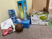 Lot overview showing boxed margarita glasses, rotary slide show, hula dancer, T-shirt and coconut cup