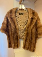 Full view of mink fur stole on hanger showing exterior fur and lining