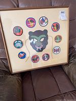 Full view of framed textile piece showing all patches and central mask