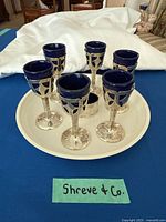 Group of six sterling aperitif glasses with blue inserts on tray