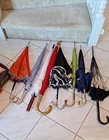 Eight umbrellas laid out showing canopy colors and handles