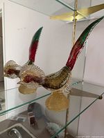Two Murano glass bird figurines on glass shelf