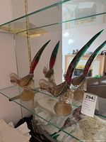Both Murano glass bird figurines on glass shelf