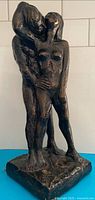 Full view of ceramic embracing couple statue on base