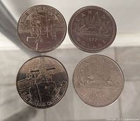 Four Canadian dollar coins laid out; two Jacques Cartier, two Voyageur dates 1977 and 1979