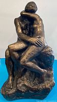 Front view of bronze-tone resin sculpture showing embracing nude couple