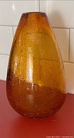 Full view of amber bubble glass vase on countertop