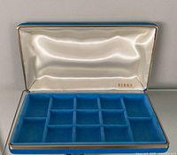Open Birks jewelry box showing blue velvet 12-section tray and satin lid