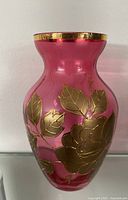 Front view of cranberry glass vase showing gold floral overlay
