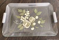 Full view of glass tray showing fruit motif and handles.
