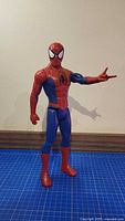Front view of 12-inch Spider-Man action figure standing on blue grid mat
