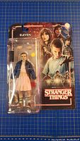 Front view of sealed Eleven action figure and accessories on Stranger Things card