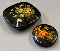 Square and round Russian lacquer boxes closed, showing painted lids
