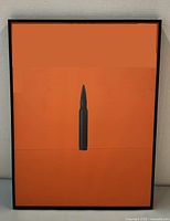 Front view of framed orange silkscreen print with black bullet image