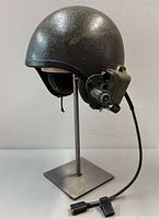 Profile view of helmet on stand showing headset and cable