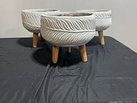 Three white textured planters on wood legs