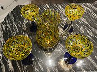 Top view of pitcher and four glasses showing multicolor pattern and blue stems