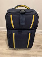 Front view of navy Nautica carry-on showing exterior zip pockets and yellow trim