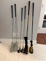 Six clubs standing against wall with headcovers visible