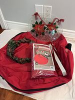 Entire lot showing red storage bag open, packaged storage bag, grapevine wreath, white hanger, glass poinsettia disc