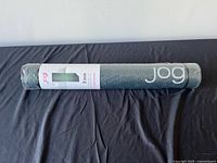 Full view of rolled yoga mat in packaging displaying brand name
