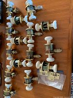 All fifteen porcelain and brass-tone door knob sets laid out on wooden surface