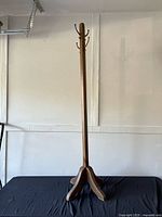 Full view of walnut wood coat rack with tripod base and metal hooks