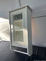 Front view of white wall cabinet showing frosted glass door and towel bar