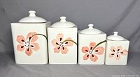 Front view of four graduated Corelle ceramic canisters showing pink flower design