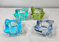 All four colored crystal votive holders displayed, showing shape and colors