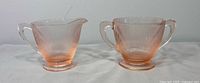 Front view of creamer and sugar bowl showing ribbed pattern and pink hue