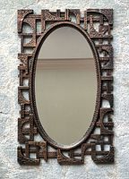 Full view of wall mirror showing oval glass and brutalist frame