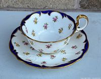 Teacup on saucer front view showing floral pattern, cobalt and gold rim