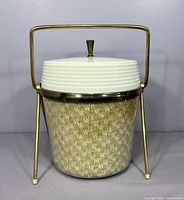 Front view of ice bucket showing raffia exterior, white lid, brass collar and handle