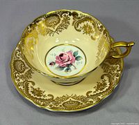 Top view of teacup and saucer showing gold filigree and pink rose center