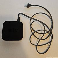 Top view of Apple TV unit showing attached power cord coiled beside