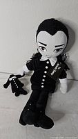 Front view of Wednesday Addams plush showing tag, outfit, and attached small plush