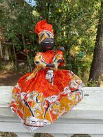 Full view of fabric doll standing on railing