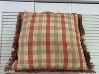 Full view of square plaid pillow with fringe trim