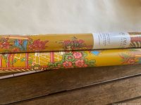 Two wallpaper rolls showing mustard colour and floral pagoda pattern