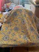 Overall view of folded Roman shade showing yellow fabric with blue floral design
