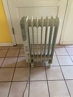 Full view of one oil-filled radiator heater standing on tile floor