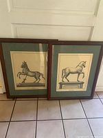 Both framed horse prints leaning against door