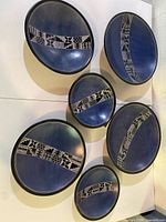 Six blue soapstone plates in three sizes displayed on wall